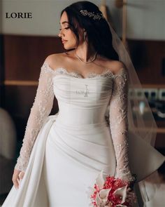 a woman in a white wedding dress with long sleeves and a veil on her head