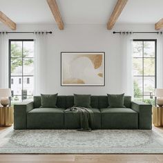 a living room with two large windows and a green couch in front of the window