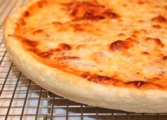 a cheese pizza sitting on top of a metal rack next to an oven grate