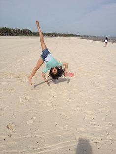 a woman is doing a handstand on the beach