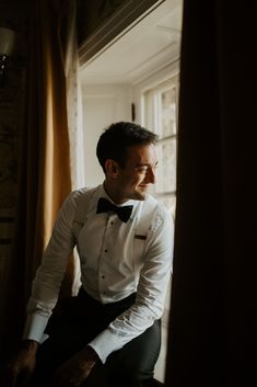 a man in a tuxedo looking out the window