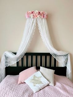 a bed with pink sheets and white curtains