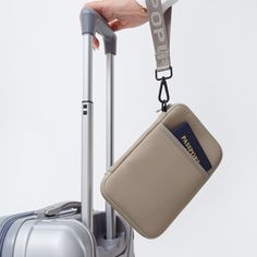 a person holding two pieces of luggage with a lanyard attached to the handle, and a passport holder hanging from it