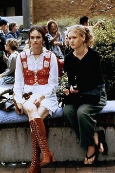 two women sitting on a bench with people in the background