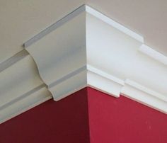 the corner of a room with red walls and white moulder trimmings