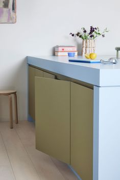 a blue counter top with some flowers and books on it in a room that has white walls