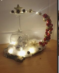 a glass vase filled with christmas decorations on top of a wooden table next to a candle holder