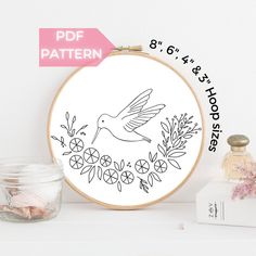 a cross stitch pattern with a bird and flowers in the hoop next to a jar