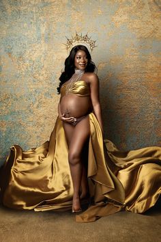 a pregnant woman in a gold gown and crown poses for the camera with her belly exposed