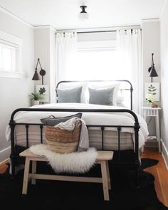 a bedroom with white walls and black metal bed frame in the corner, along with a bench