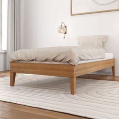 a bed sitting on top of a wooden floor next to a white rug and window