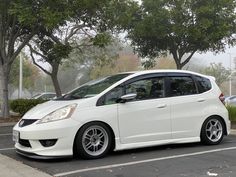 a white car parked in a parking lot next to trees