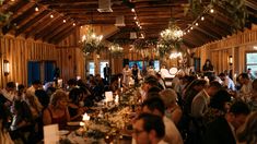 a large group of people sitting at tables in a room with lights on the ceiling