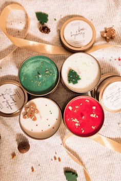 six small tins filled with different types of christmas candles and ribbons on top of a table