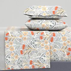 three pillows are stacked on top of each other with an orange and white flower pattern