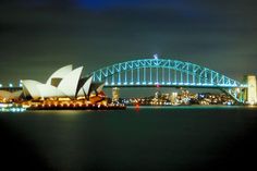 the sydney opera house and harbour bridge lit up at night