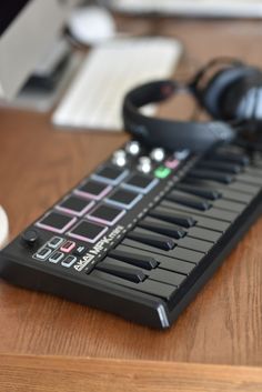 a keyboard and headphones sitting on top of a wooden table