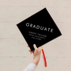 a person holding up a graduation cap with the word graduate written in black on it