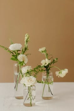 three clear vases with white flowers in them