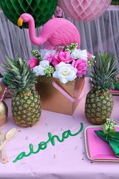 a table topped with pineapples and pink flowers