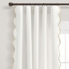 white curtains with scalloped edges hanging on a curtain rod