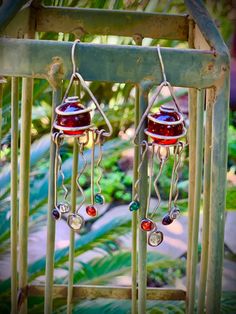 the earrings are hanging from the metal bars in front of green plants and trees,