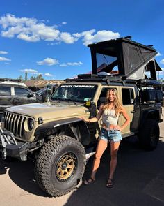 a woman standing next to a jeep in a parking lot