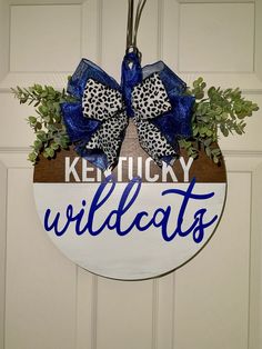 a kentucky wildcats sign hanging on a door with blue and white bowknots