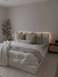 a bed with white sheets and pillows in a bedroom next to a lamp on the wall