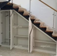 an open closet under the stairs in a room with white walls and carpeted flooring