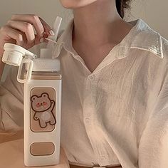 a woman sitting at a table with a bottle and toothbrush