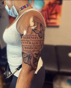 a woman with a butterfly tattoo on her arm and the words serenity, courage, and wisdom