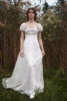 a woman in a white dress standing in tall grass