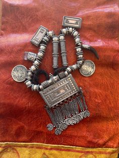 Here is an amazing, antique necklace from Oman.  The main pendant measures approximately 5 3/4" (14,55 cm) long, including the dangles and ~ 3 7/8" (9,85 cm) wide.  This is a truly old piece and the silver is high grade with fantastic patina and wear patterns.  It has two amulets, one of glass and one of horn (likely antelope).  This piece is strung on what seems to be woven goat hair.  The central amulet opens.   This piece weighs ~ 436 grams. Unique Festival Necklace With Coin Pendant, Festival Coin Pendant Necklace, Traditional Medallion Jewelry For Ceremonial Occasions, Traditional Handmade Antique Silver Necklace, Bohemian Long Necklace For Ceremonial Occasions, Bohemian Long Necklace For Ceremonies, Bohemian Coin Pendant Necklace For Rituals, Traditional Coin Pendant Necklace For Festivals, Bohemian Ceremonial Necklace With Oxidized Finish