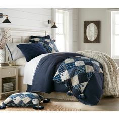 a bed with blue and white comforters in a bedroom next to two pillows on the floor