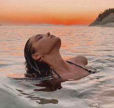 a woman floating in the water at sunset