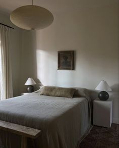 a bed sitting in a bedroom next to two lamps on either side of the bed