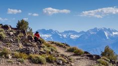 a person sitting on top of a mountain with mountains in the background