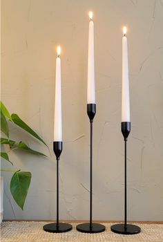 three white candles sitting on top of black bases