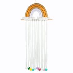 a rainbow mobile hanging from the ceiling with pom poms on it's sides