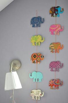 an elephant themed mobile hangs on the wall next to a lamp in a child's room