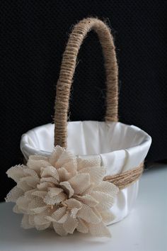 a white basket with a flower on the handle and some burlocks around it