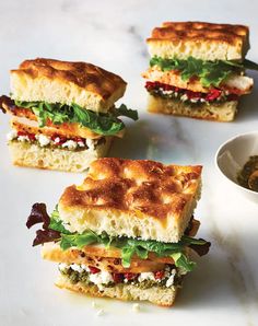 four sandwiches with different toppings on a white plate next to a bowl of salsa