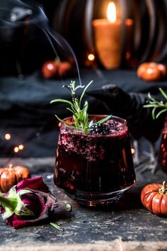 a glass filled with liquid sitting on top of a table next to some pumpkins