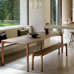 a wooden table sitting next to a window in a living room under a light fixture