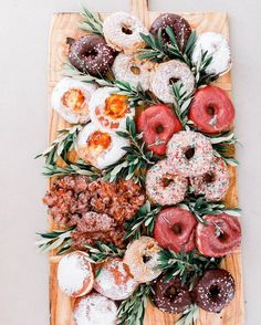 donuts and other pastries are arranged on a cutting board with sprigs