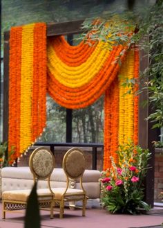 an orange and yellow flower decorated stage with chairs