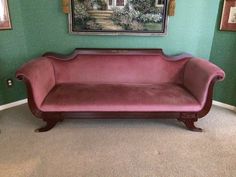 a pink couch sitting in front of a painting on the wall