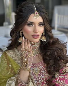 a woman in a bridal outfit with her hands on her face and wearing jewelry