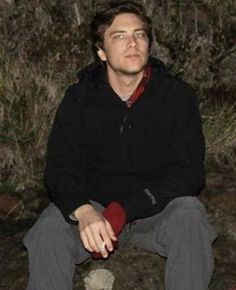 a man sitting on top of a rock next to a fire hydrant at night